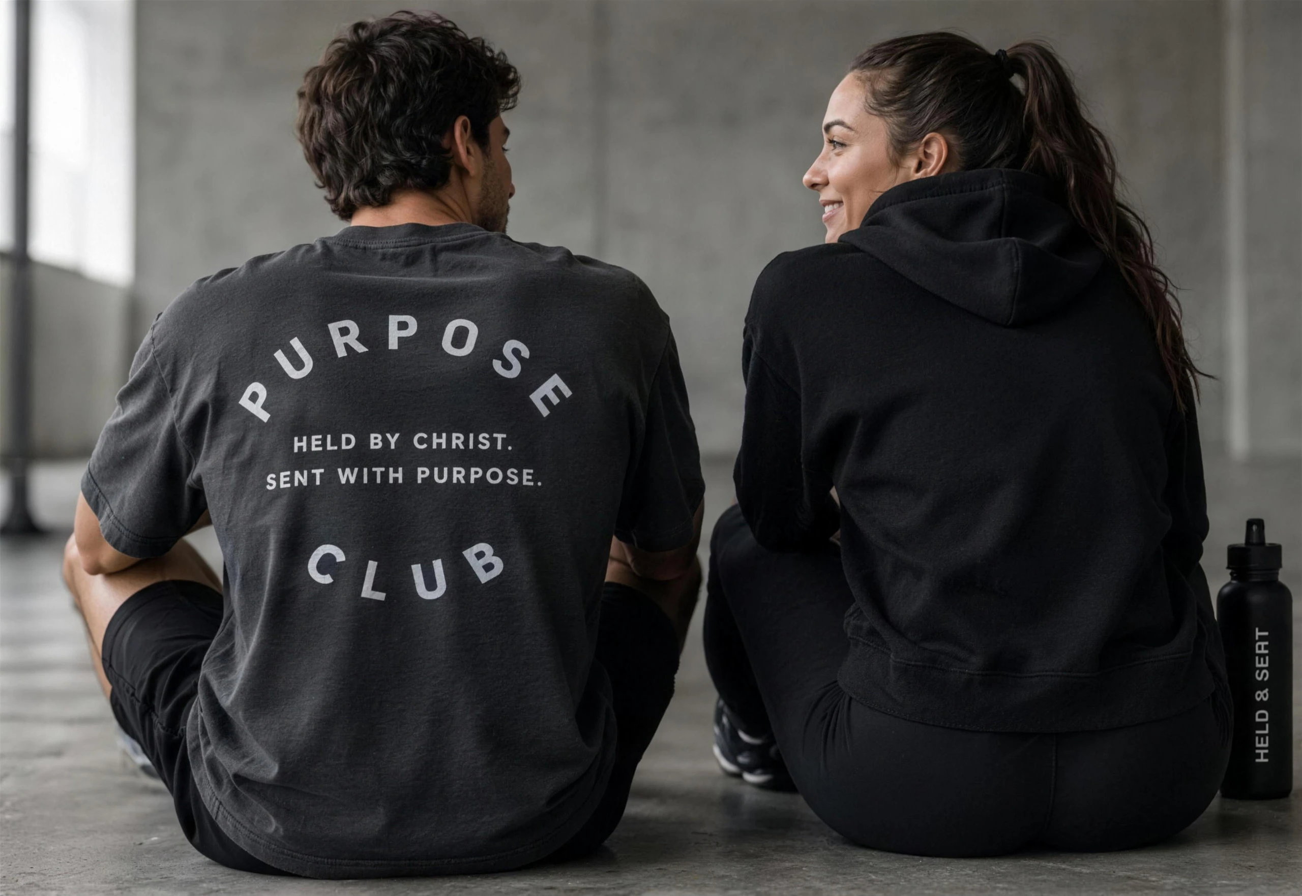 Two people seated, backs turned, wearing HELD & SENT